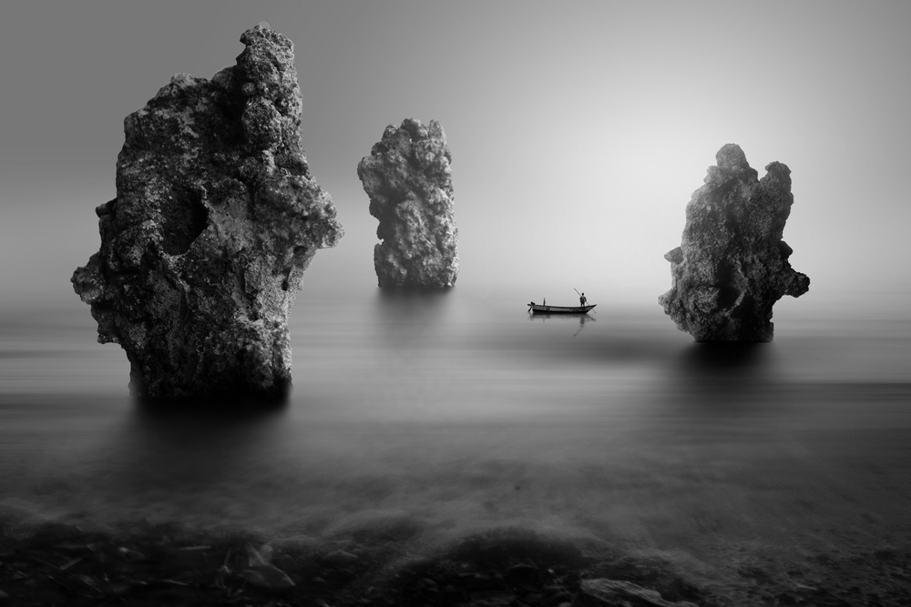 Dramatic black-and-white scene of a lone fishing boat. Impressive monochrome landscape photography achieved in program mode.