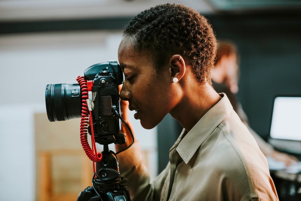 black woman taking photos using DSLR camera.