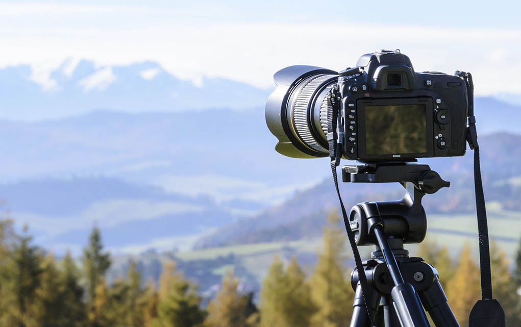 camera and tripod with mountain in background.