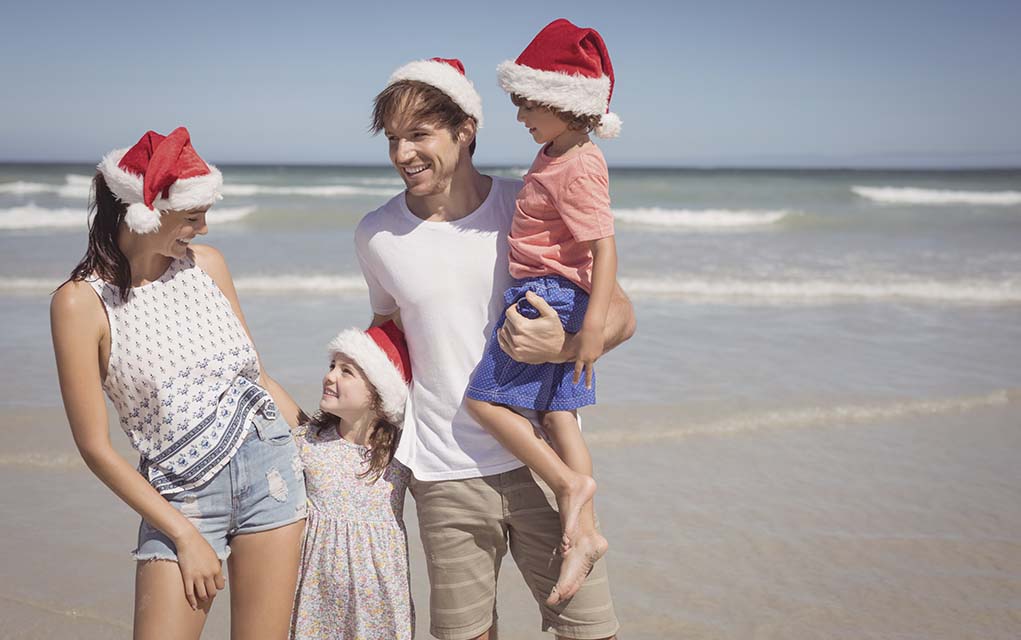 family in Santa hats at the beach