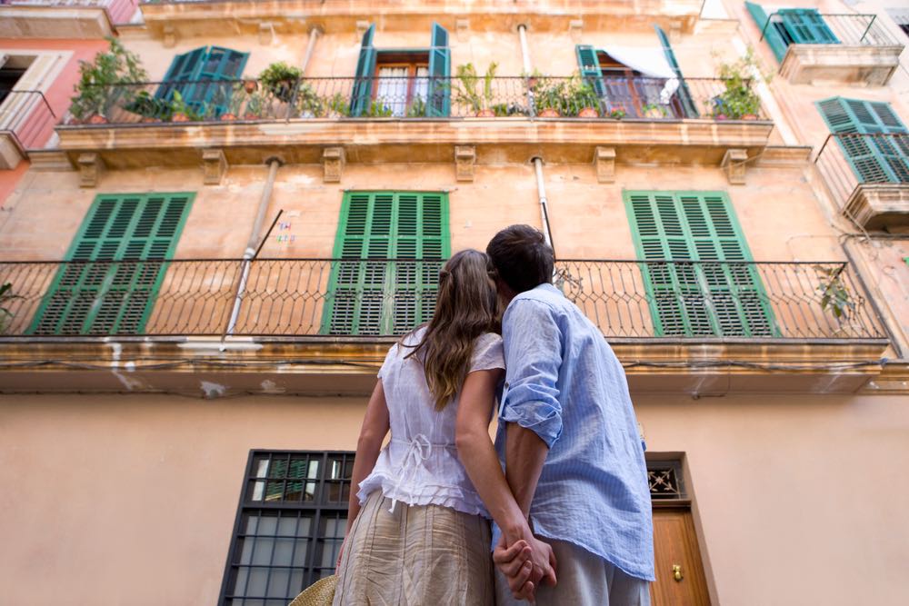 A young couple surveying the facade of a building. Low-angle photography evoking feelings of romance, hope, and awe.