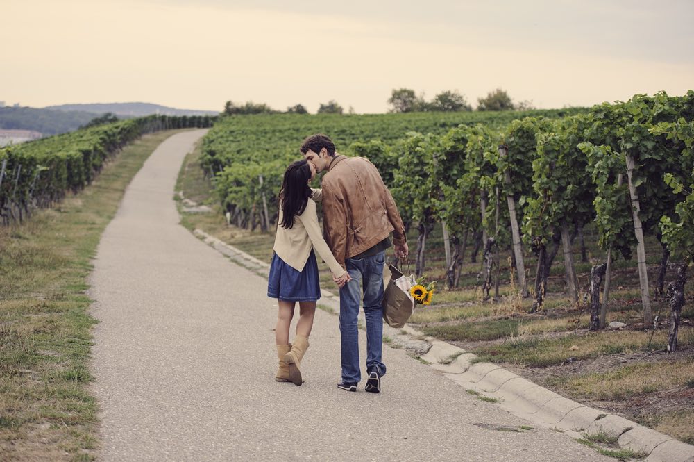 An engaged couple being photographed in the middle of a vineyard.