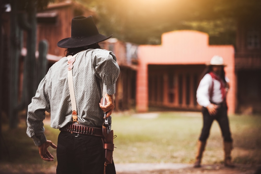 A cowboy angle shot of two actual cowboys having a showdown with revolvers. 
