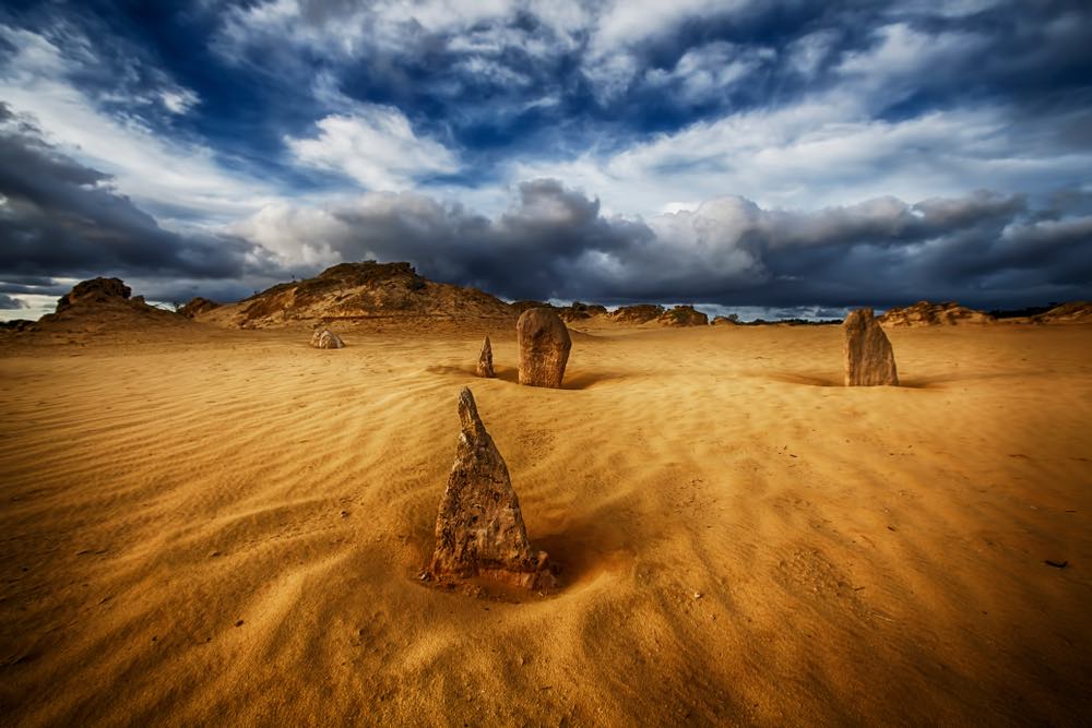 Wide-angle landscape photograph. Australian desert in color, cloudy sky.