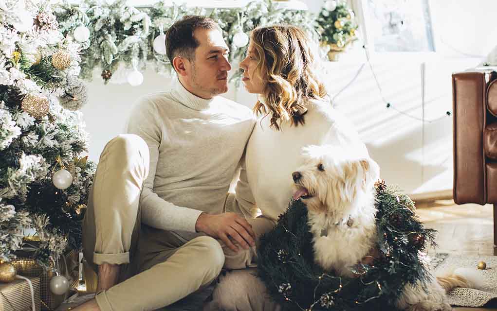 romantic couple with dog and holiday wreath
