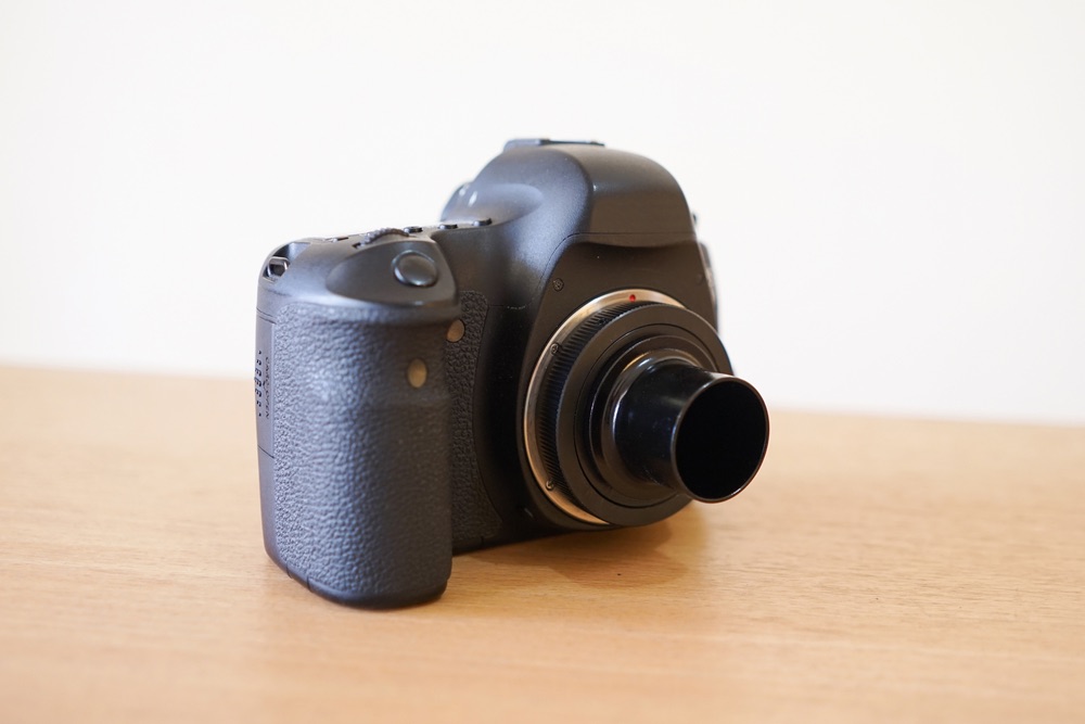 A DSLR camera with a T-ring adapter for telescope mounting attached.