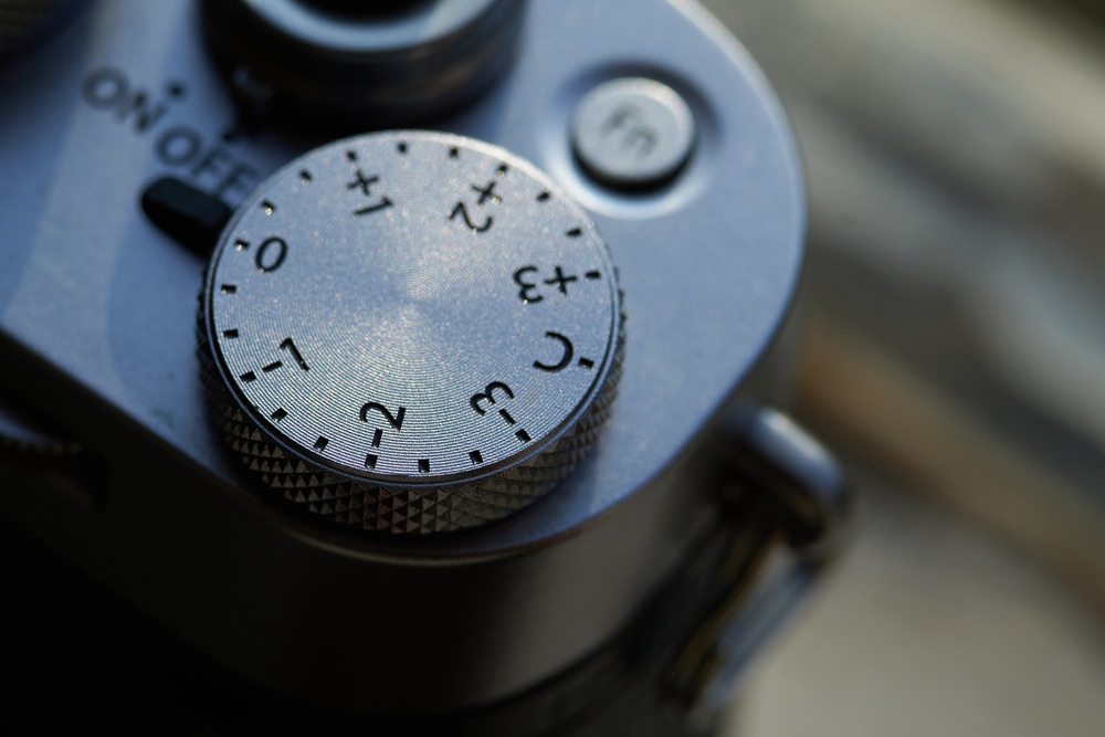 Close-up view of the exposure compensation dial of a modern digital mirrorless camera. Plenty of camera models nowadays allow you to control both EV compensation and FEC via the same dial.