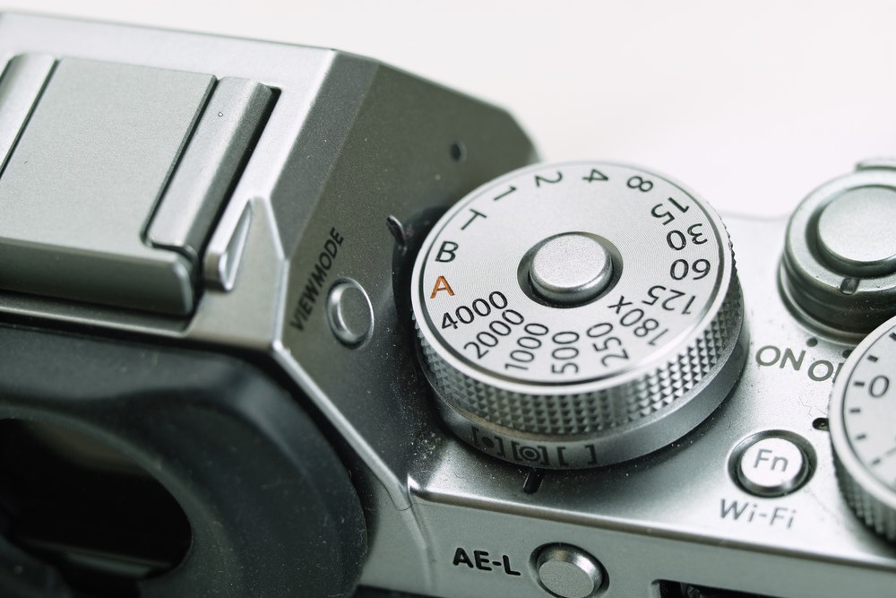 A close-up view of a Fujifilm mirrorless camera's manual shutter speed dial. 'B' for bulb mode selected.