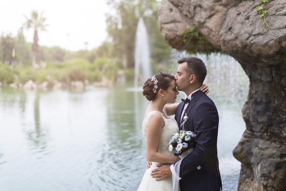 A bride and groom in a scenic location underneath a rock arch.