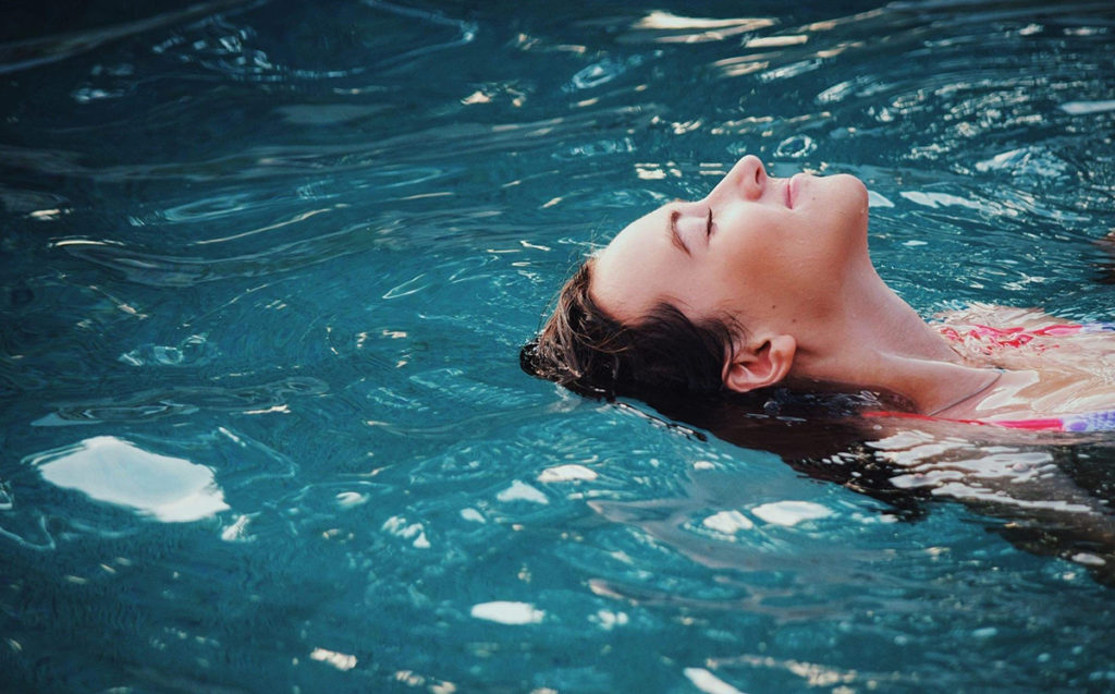 relaxing photo of woman floating in a pool.