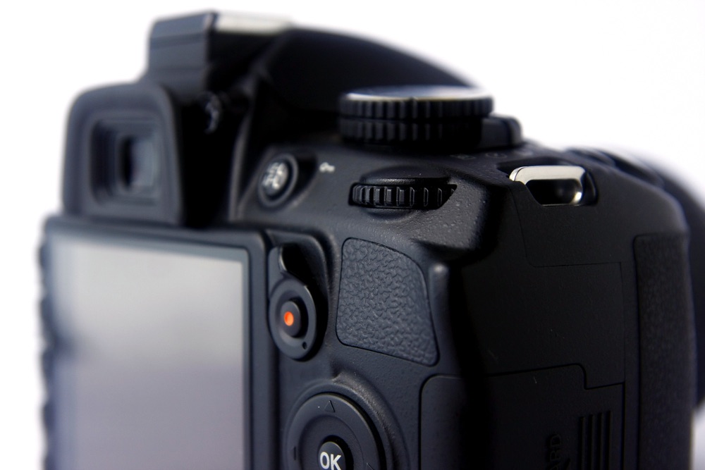Close-up view of the rear of a contemporary compact DSLR, showcasing the command dial and the rear LCD.