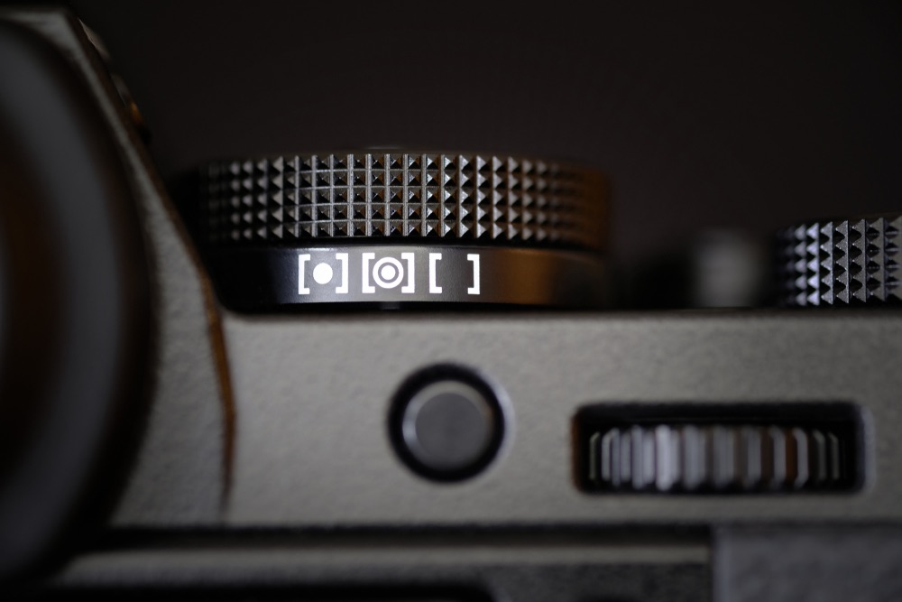 A close-up view of the metering mode dial of a contemporary digital camera.