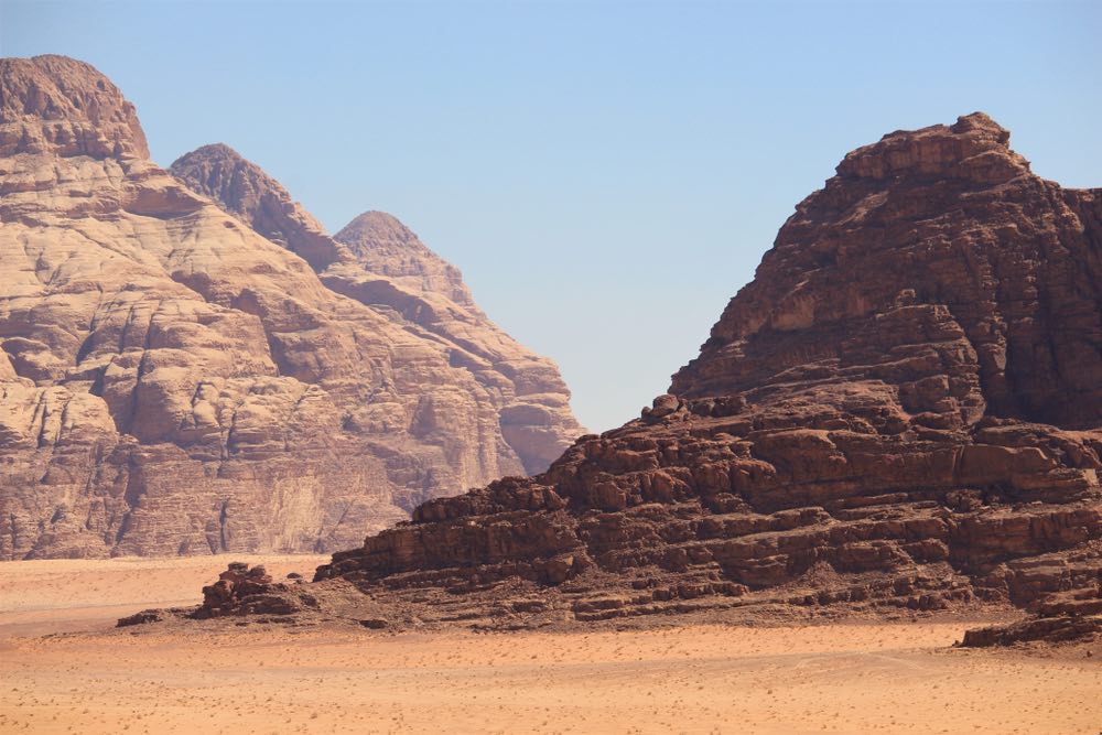 A desert landscape featuring prominent tall, cliff-like dunes. Color landscape photography with a dominant middle ground.