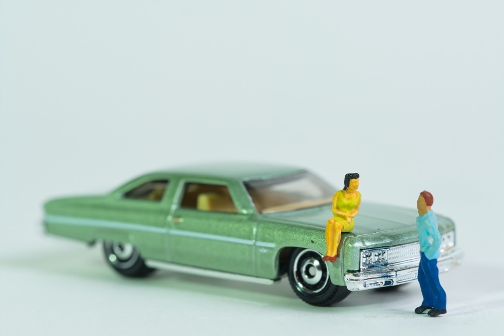 A miniature scene depicting a couple posed against the prop of a small model car. An example of combining multiple different kinds of props to create a story.