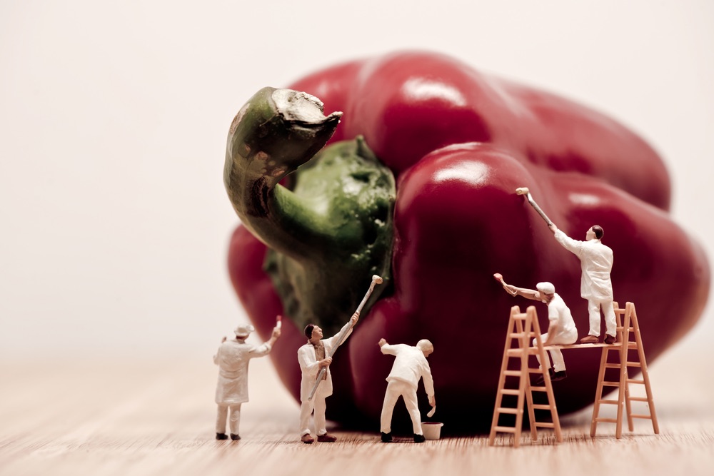 A group of miniature painters hard at work on a red pepper. Abstract miniature photography with a witty theme.