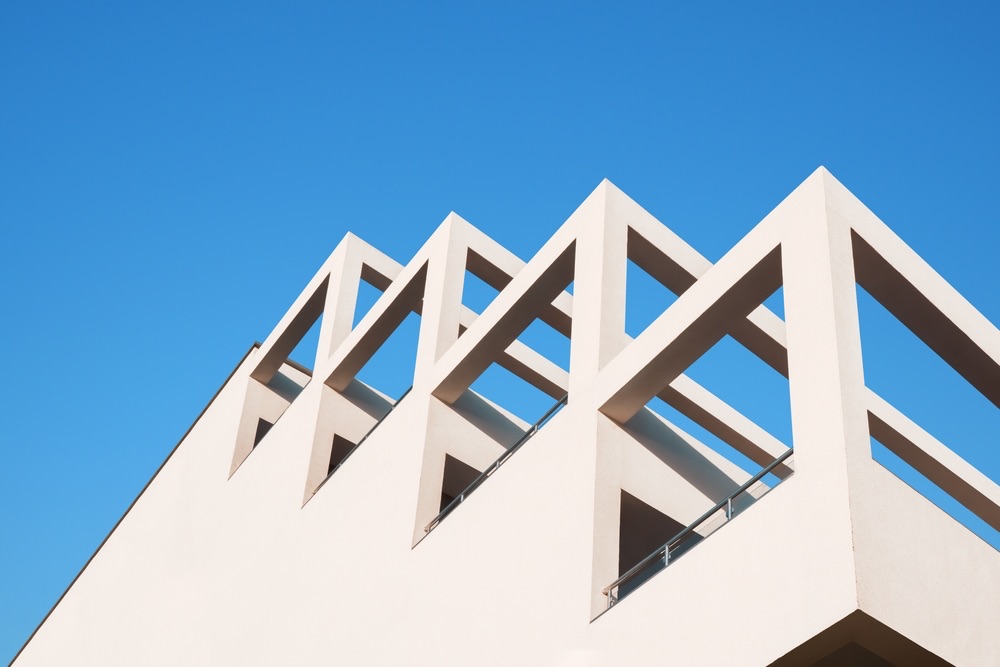 An upwards angle of a building facing the sun. There are several levels of angles that create a simple image. minimalist architecture photo. 