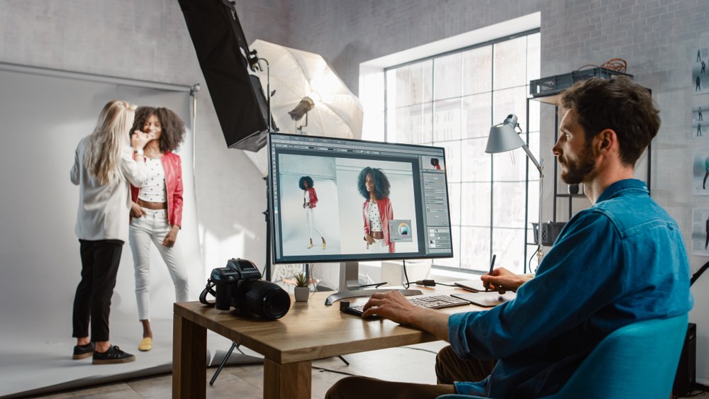 A modern and professional studio photographer touching up a portrait session using multiple input devices and an all-in-one post-processing suite. Concept of contemporary photography editing in the studio.