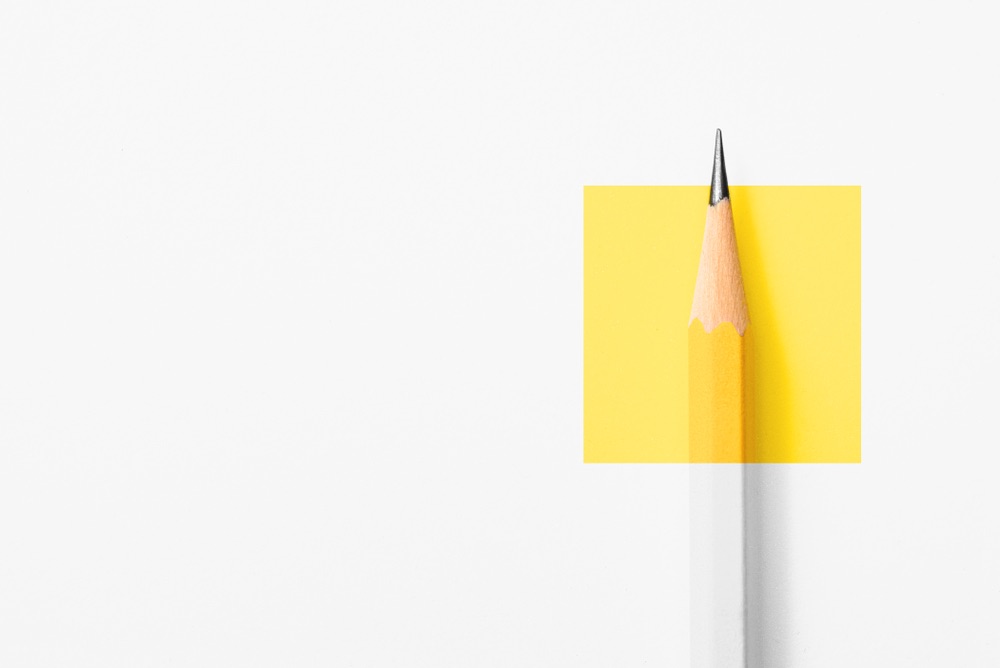 A pencil sits on a white surface. The top third of the pencil is highlighted in yellow and showing a normal color palate. The bottom two thirds are seemingly painted white.  