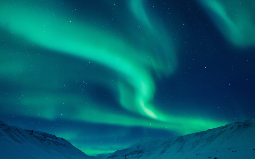 The aurora borealis as seen over a mountain valley in Svalbard, Norway.