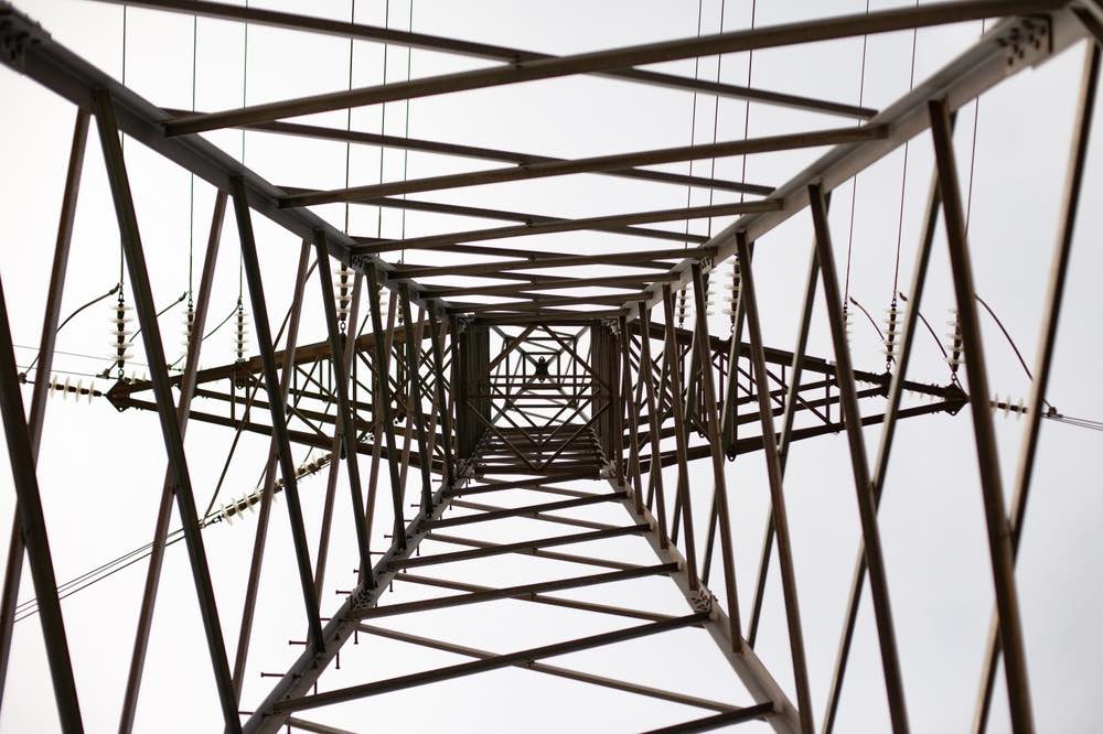 Low-angle photograph of power lines. Geometric structures viewed from below.