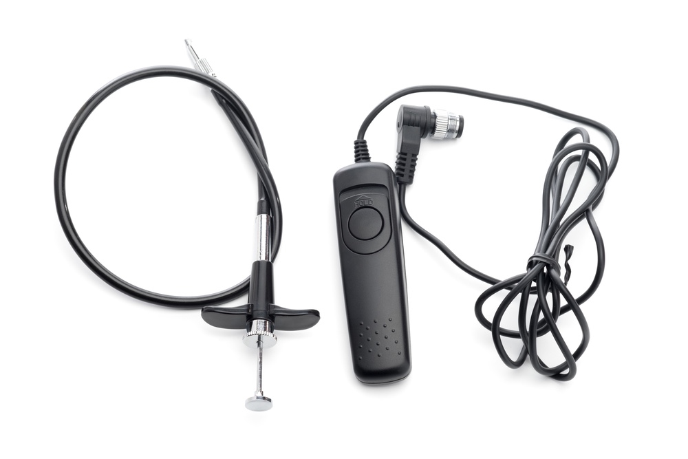 Two types of remote shutter release cables side-by-side. An old manual plunger-type on the left, and a more modern button-type with a contemporary thread mount on the right.