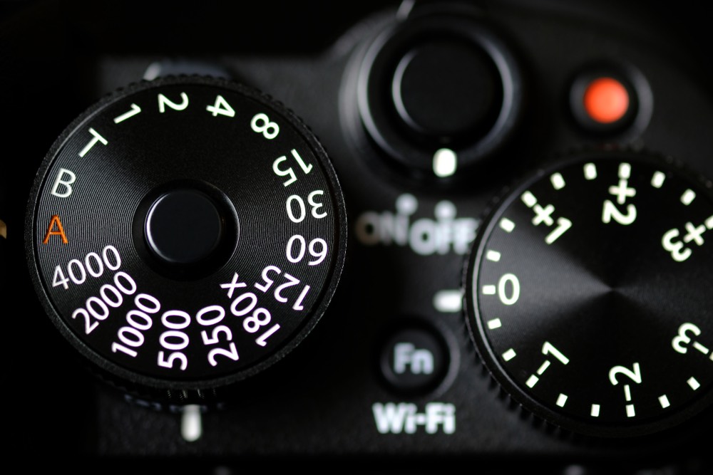 Closeup view of a modern digital camera's shutter speed dial. Exposure compensation dial to the right.