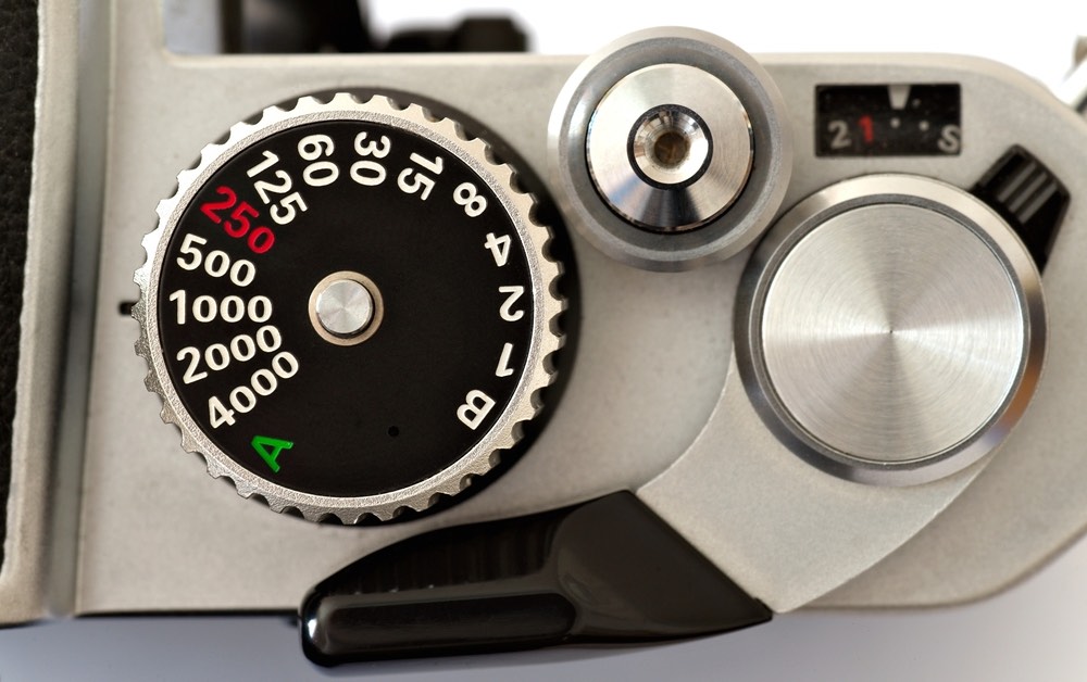 Top-down view of the shutter speed dial on a vintage SLR camera.