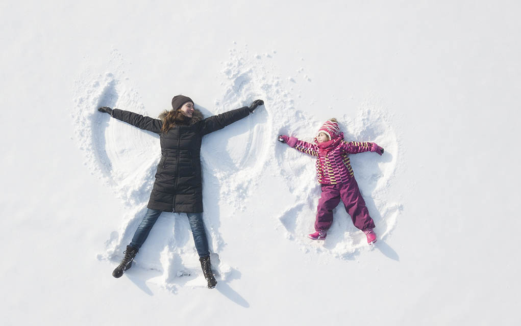 woman and child make snow angels