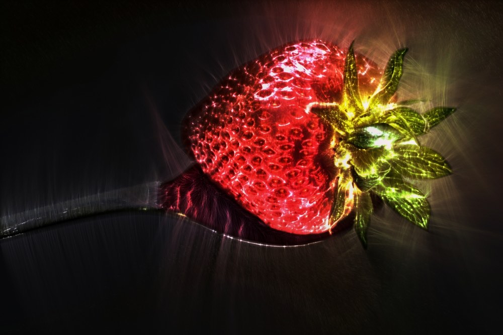 A Kirlian photograph of a strawberry resting on a spoon. Color Kirlian photography.