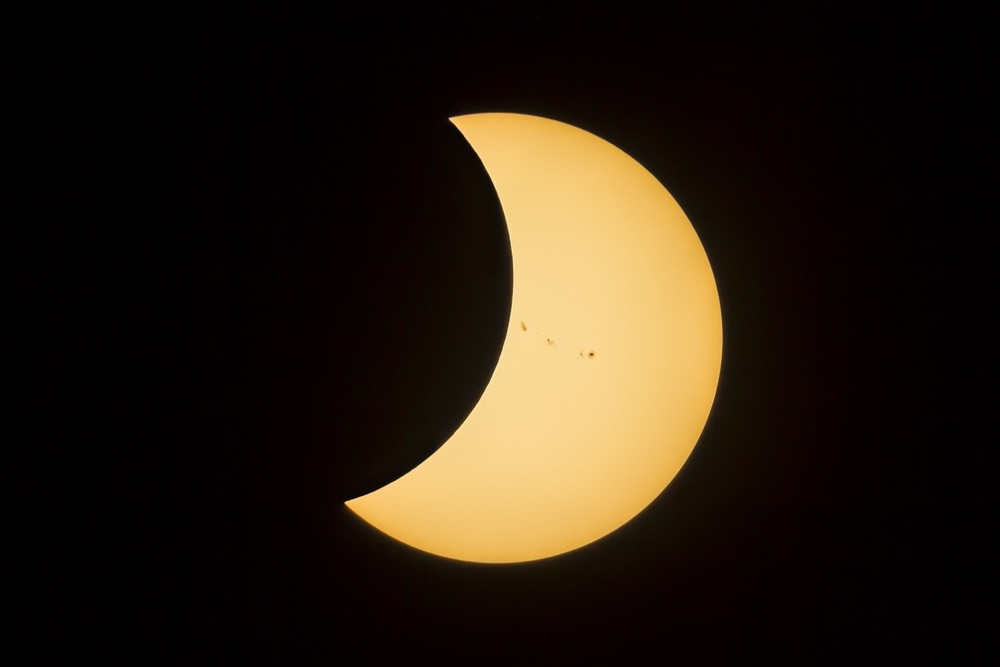Photograph of solar eclipse and sunspots on surface of the Sun.