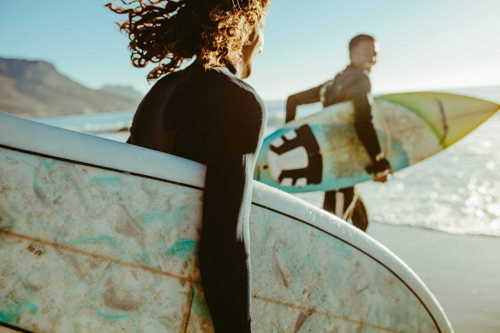 A pair of surfers heading out to sea. Casual sports photography in a non-competitive setting. Moderately thin depth of field.