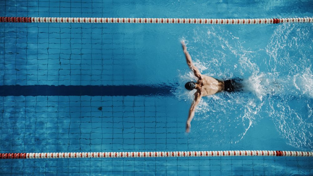A male swimmer frozen in action. Sports photography with an aerial top-down perspective.