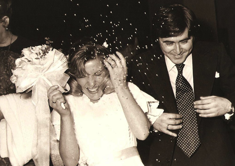 A vintage black and white photo of a bride and groom getting showered with confetti.
