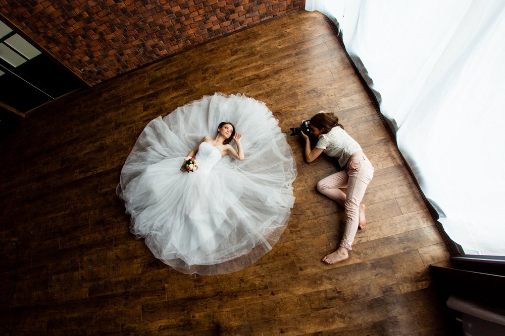 An abstract wedding photography composition involving the bride and photographer on the floor. An example of advanced, daring, and artistic wedding photography techniques.