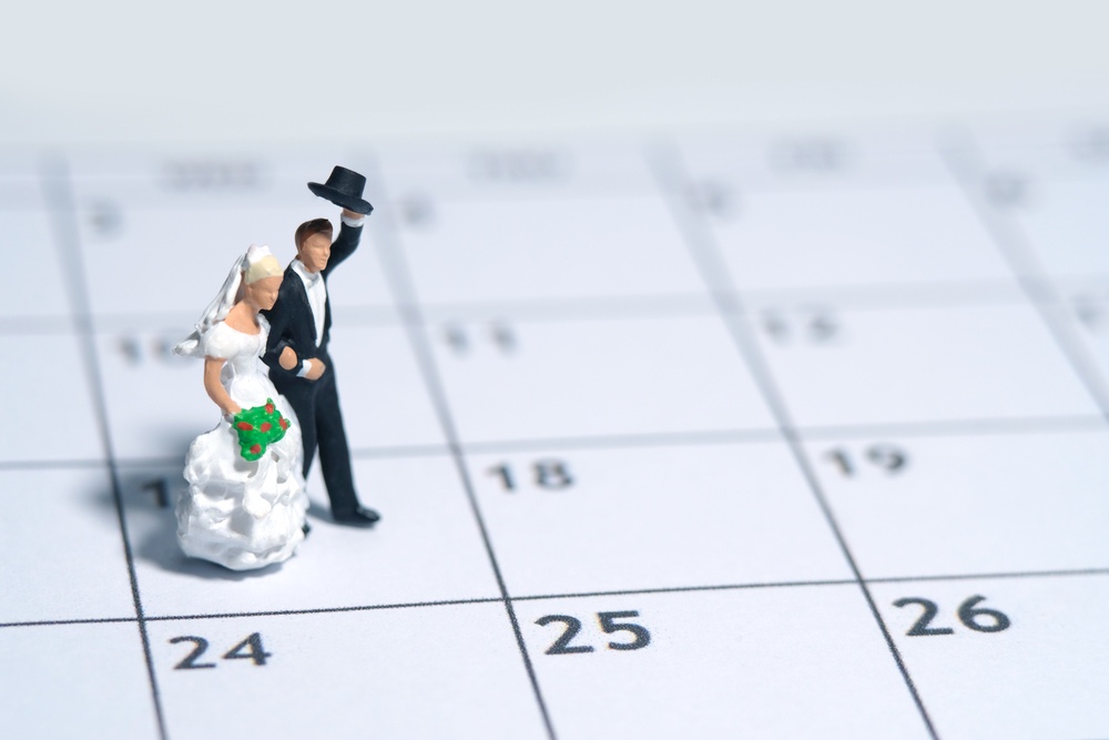 A pair of bride and groom mini figurines on top of a calendar.