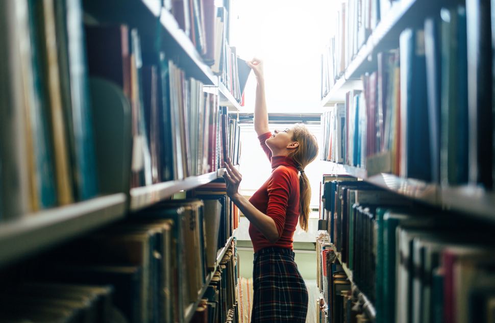 woman looking for books in a library.